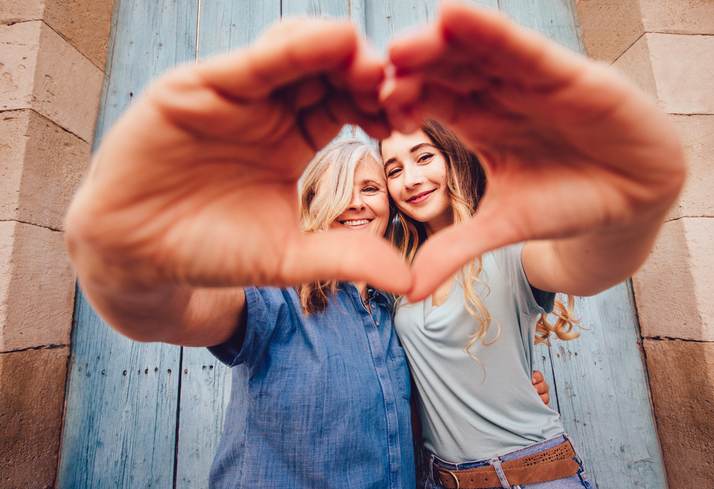 Smiling senior mother and daughter making a heart shape with their hands