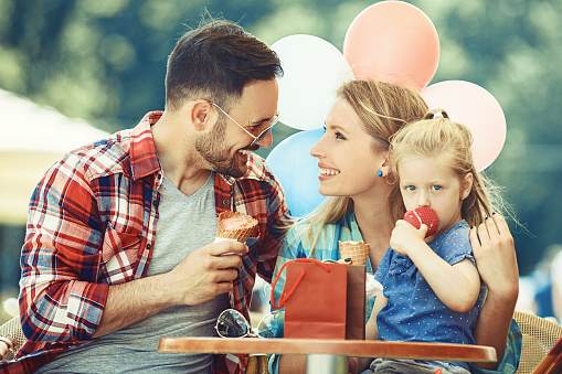 Happy family enjoying ice-cream in cafe after shopping.